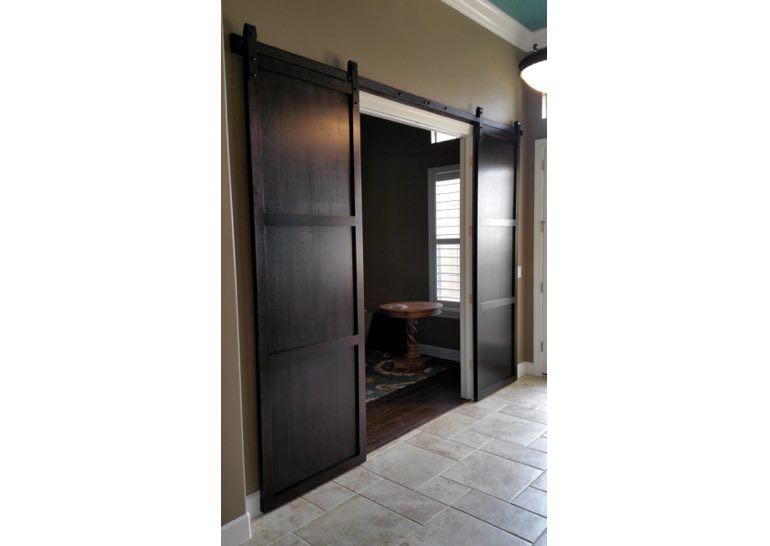 Dark brown sliding barn door covering home office entry 